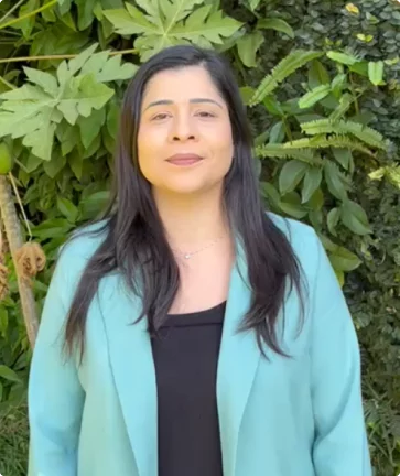 Imagem da avaliadora. Uma mulher morena de braço cruzado com uma camiseta cinza